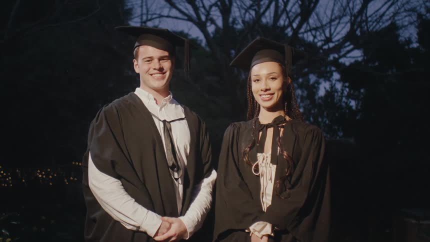 Man and woman in graduation gowns posing for photos
