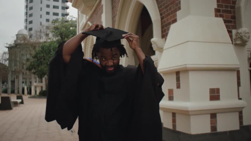 Man putting on graduation cap