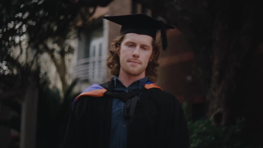 Man in full academic dress poses for the camera