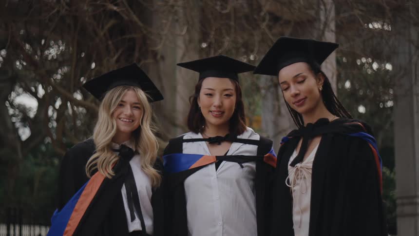 Three young women posing in graduation outfits