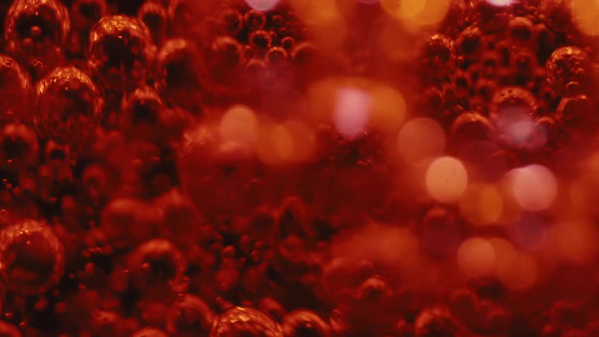 A closeup of red air bubbles rising inside a clear liquid