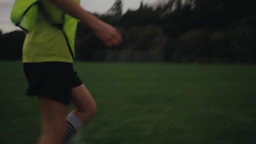 Girl running driving the ball while playing soccer and finishing off the goal