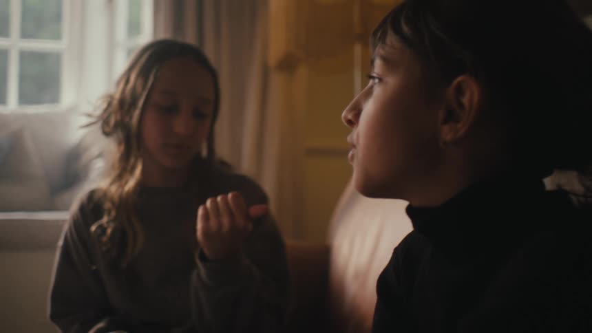 Two teenage girls sitting in the living room floor having a conversation