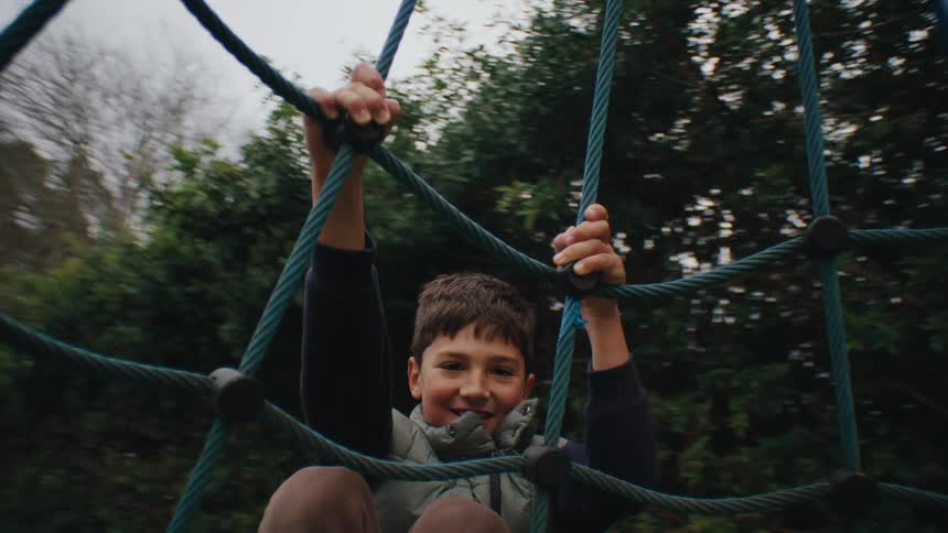 Boy holding onto a spinning toy in a playground
