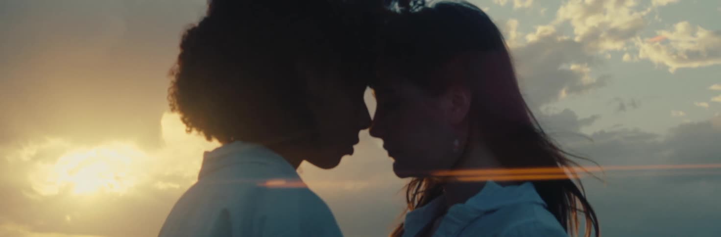 Two women with their eyes closed and their foreheads together in a romantic way