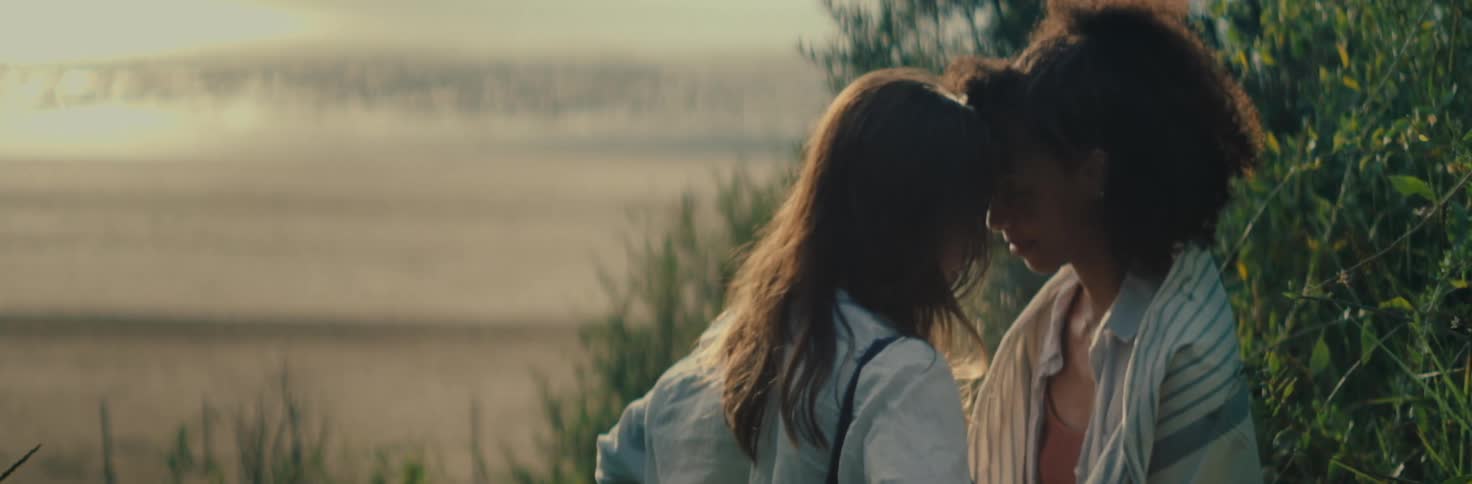 Two women face to face in romantic contact on the sand of the beach