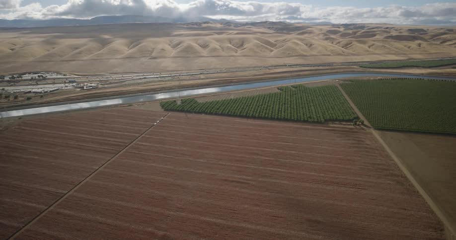 Aerial of agricultural land near a river and hills in the distance