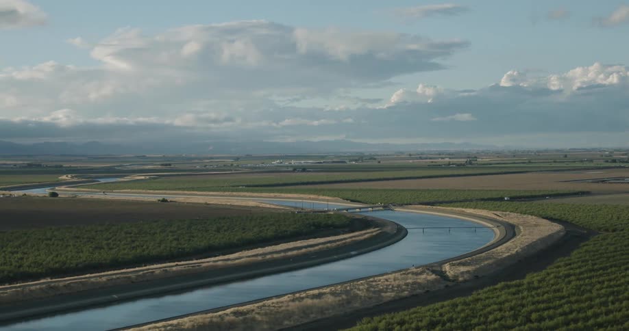 Aerial view of a canal surrounded on both sides by agricultural fields