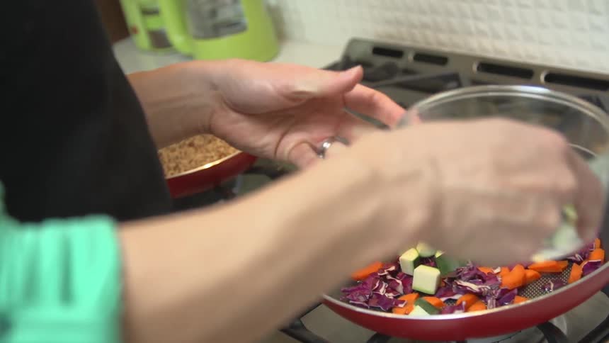 Woman pouring vegetables into a pan