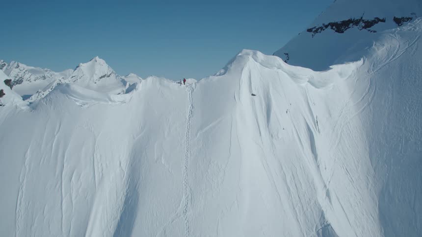 A skier stands on a steep snowcovered mountain slope