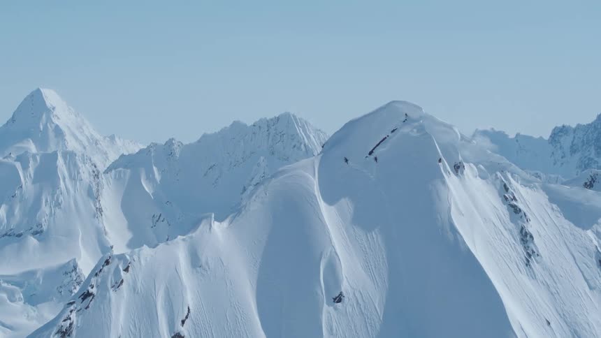 An aerial view of a person climbing a steep mountain side to reach the summit