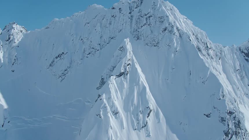 A person climbing the snow covered slopes of a mountain to reach the summit