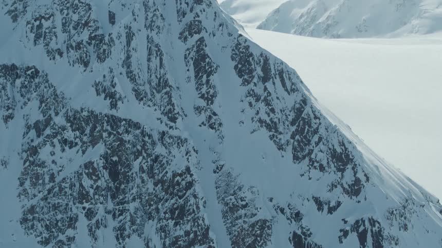 A lone skier is making their way down the steep snowcovered slope leaving faint tracks on the mountainside