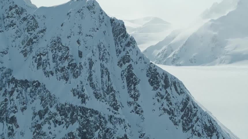 Aerial view of a snowy mountain and a person skiing