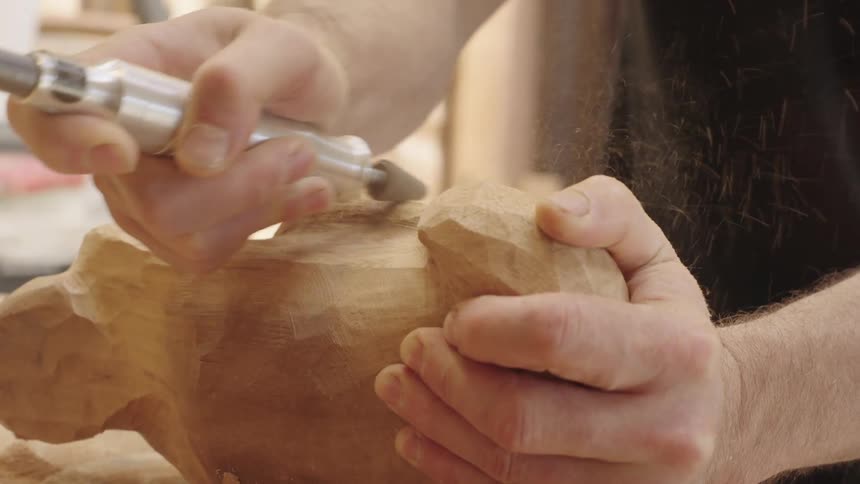 Hands of a carpenter with a tool shaping a piece of wood