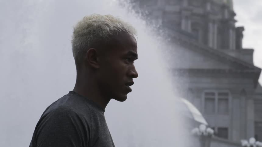 Side portrait of a man concentrating next to a fountain in a square