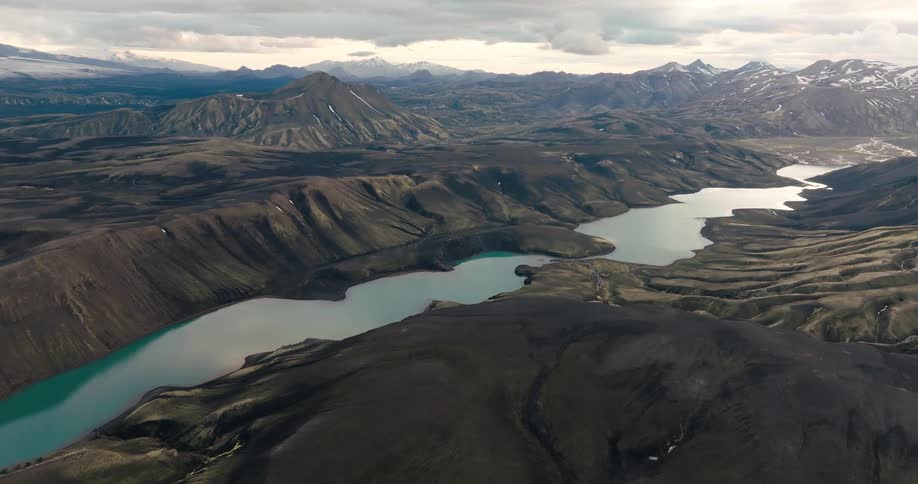 Aerial view of a dramatic landscape with rolling hills and a winding river of varying shades of blue