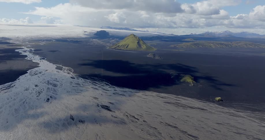 Aerial shot of a black soil landscape with a mountain valley in the background