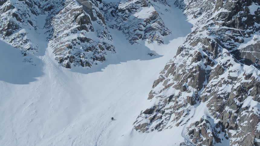 Person in ski gear climbing a snowy mountain