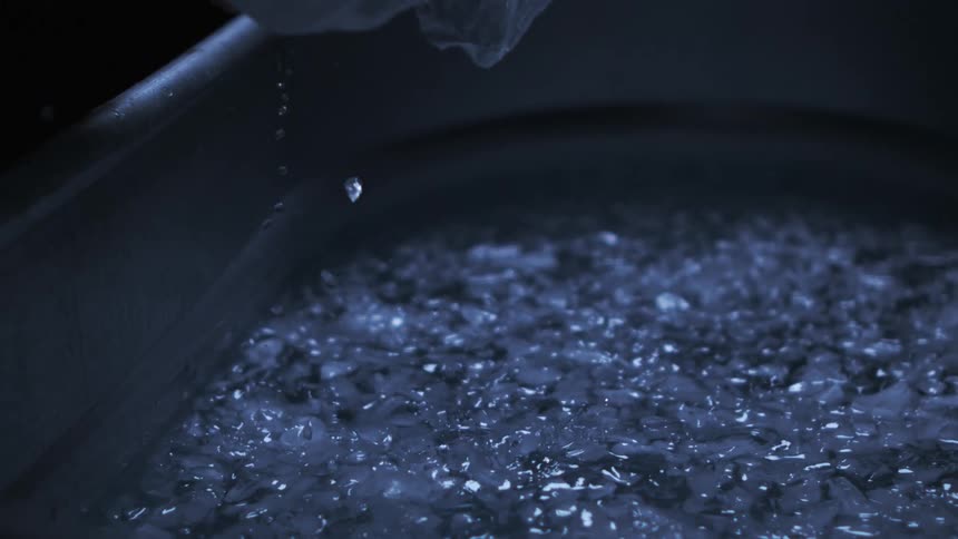 Icy looking blobs of water drop off of a mans face and land in a metal bin