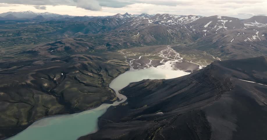 Aerial view of a vast mountainous landscape with a winding river and a lake