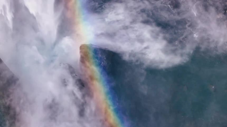 Waterfall free falling over rocks and rainbow