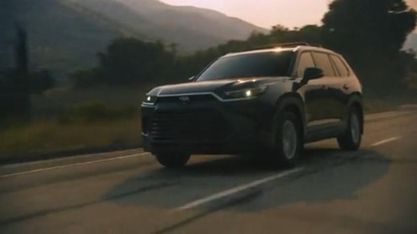 A black suv drives down a winding road at sunset