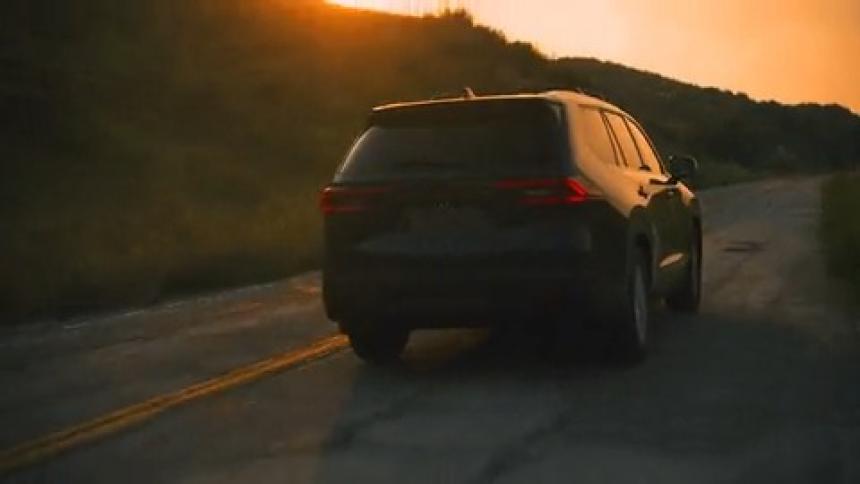 Camera booms down over SUV driving into the sunset