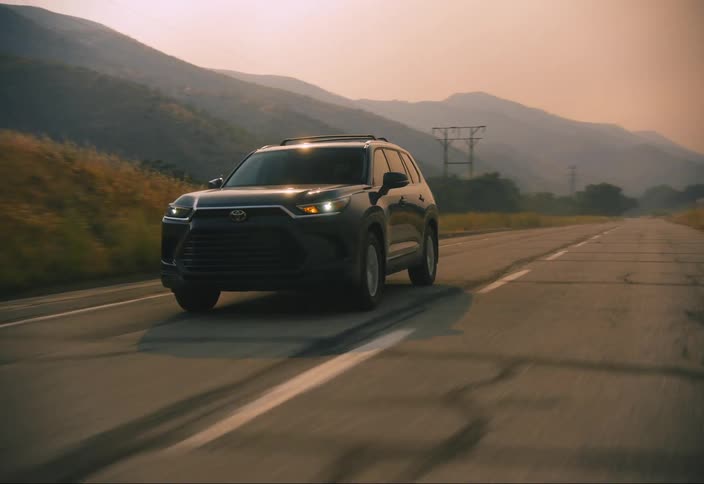 Black suv driving on a road with a mountainous landscape in the background