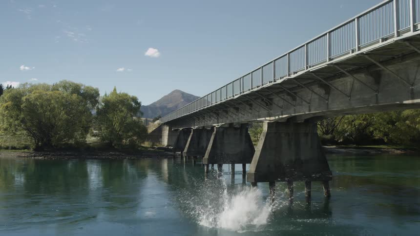 Man does a jump off a small bridge into the water below