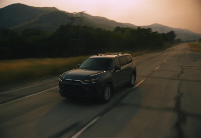 Car driving on a road with dry grass on the sides during sunrise