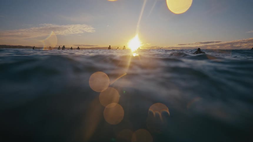 Surfers in the ocean at sunset