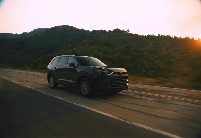 Suv vehicle moving on a road with hills in the background and a sunset