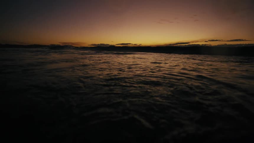 Waves move in the ocean at sunset