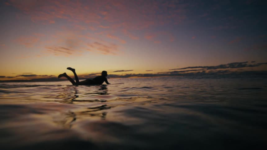 Silhouette of a surfer on a board in the sea