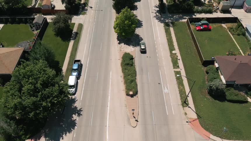 A car is driving down the neighborhood street