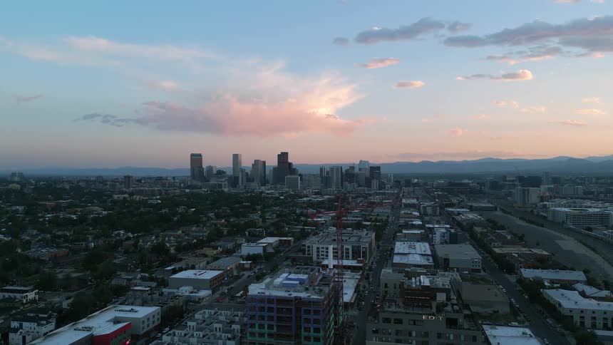 Aerial view of a city at dusk with buildings in the foreground and skyscrapers in the background