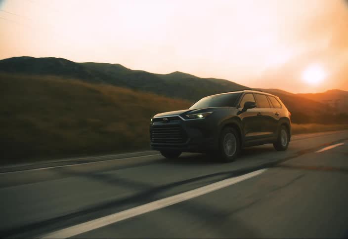 A black suv drives down a highway at sunset