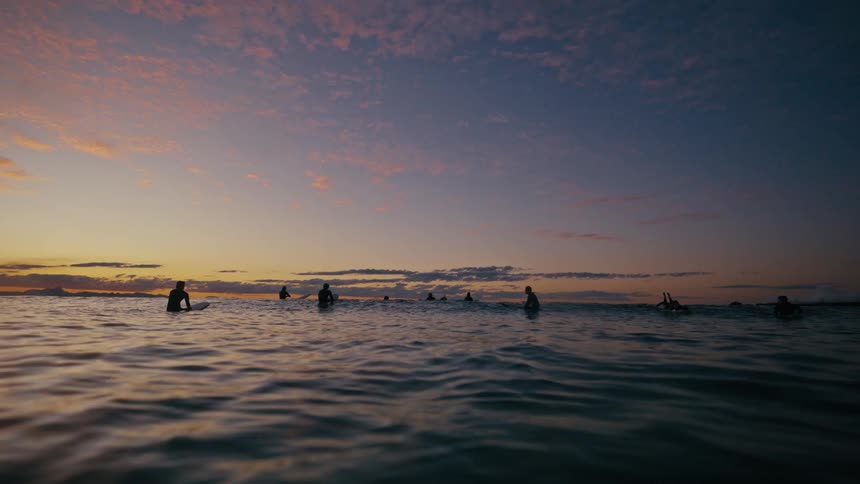 A group of people in the ocean during sunset
