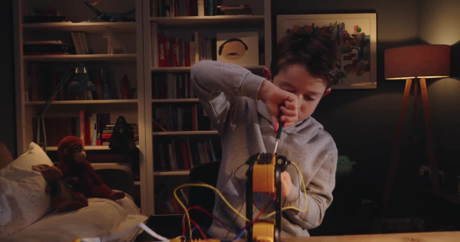 A child is working on a gadget using a screwdriver