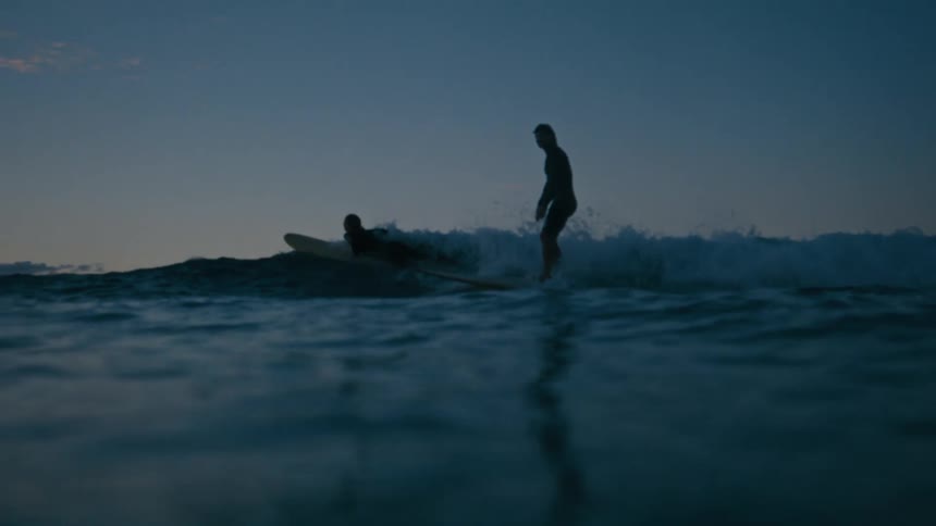 Silhouette of a person surfing a wave during twilight