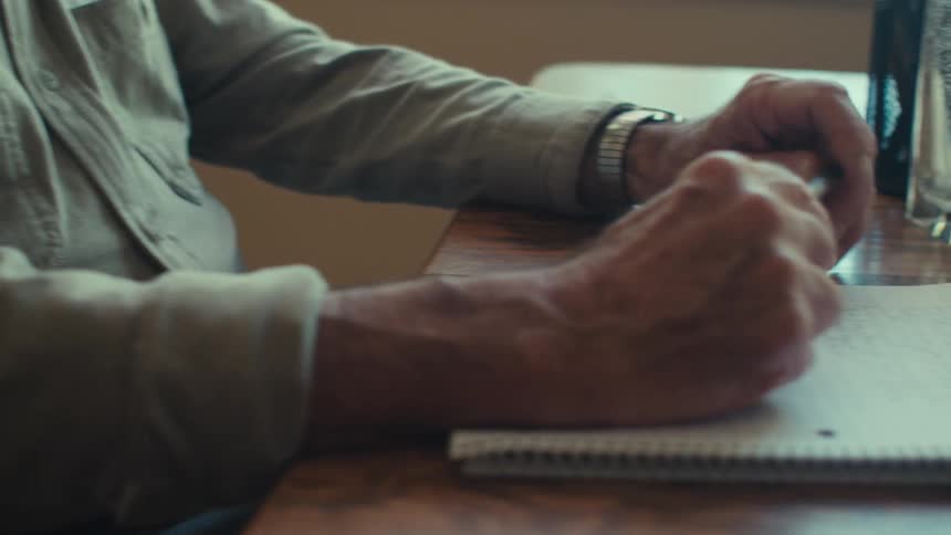 Happy sitting elderly man holding a pen