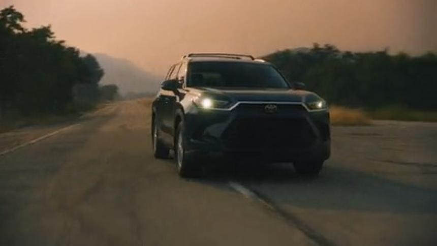 Black large SUV changes lanes on a highway under a smoky sky