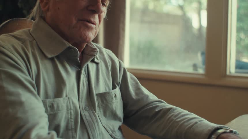 Elderly man writing sitting at the table