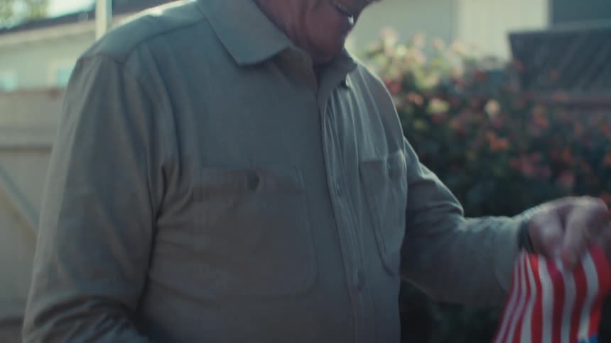 Cheerful elderly man holding a small american flag