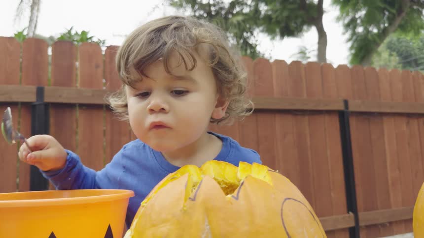 Little boy holding a spoon and playing with a pumpkin