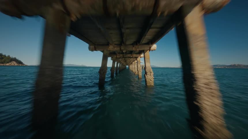 FPV Drone Flight Under Large Wooden Pier Stretching from Coast into the Ocean