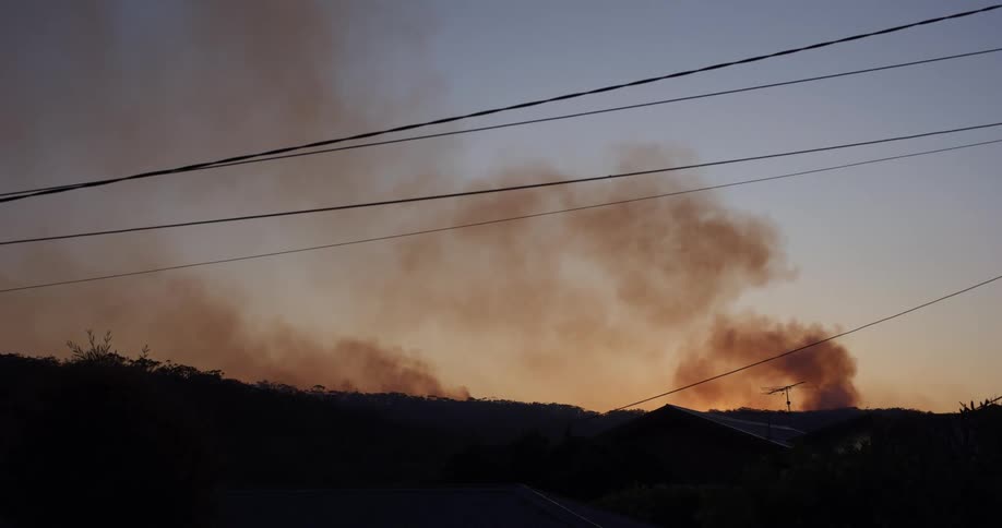 Smoke is rising over the hill at sunset