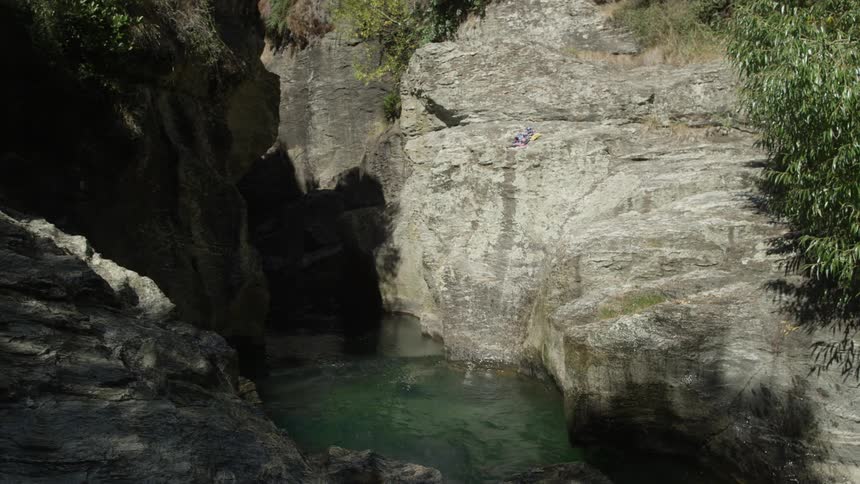Man dives off rocks into the water below