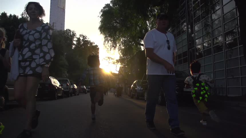 People walking and running down a street at sunset
